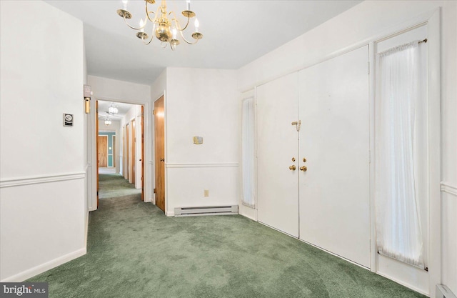 carpeted empty room featuring baseboard heating and a chandelier