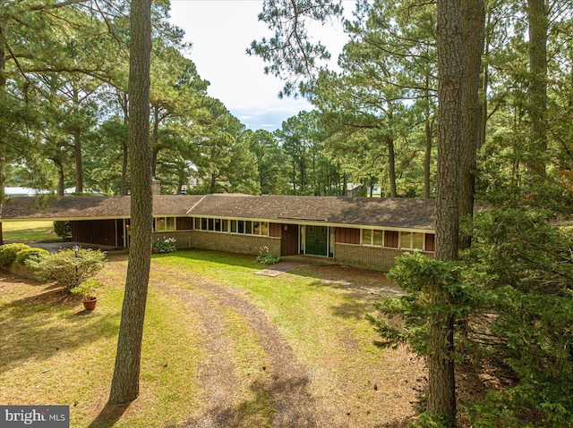 ranch-style home with a front yard, brick siding, and dirt driveway