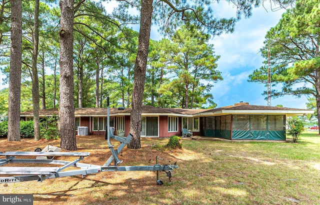 ranch-style home with a sunroom, a front lawn, and central AC unit