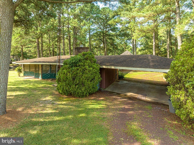 exterior space with a chimney, a carport, and a yard