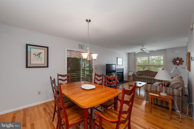 dining room with ceiling fan with notable chandelier and light wood-type flooring