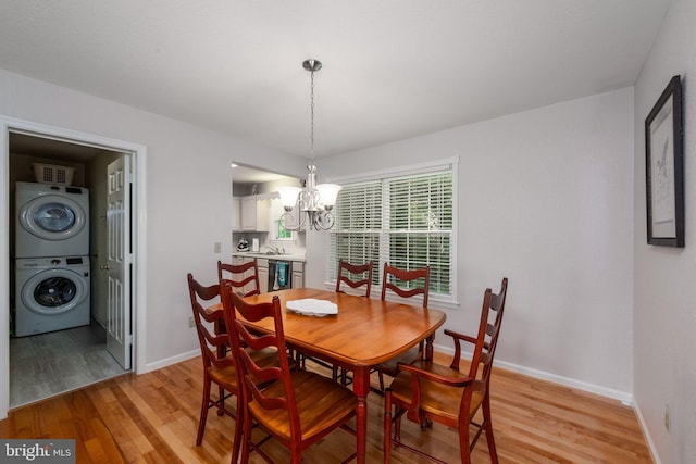 dining space featuring stacked washer and dryer, sink, an inviting chandelier, and light hardwood / wood-style flooring