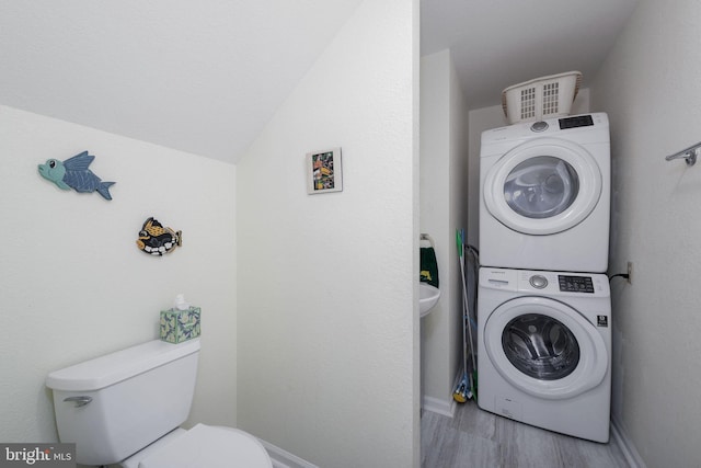 washroom featuring stacked washing maching and dryer and light hardwood / wood-style floors