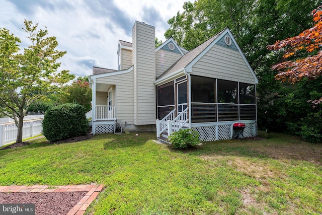 rear view of property featuring a yard and a sunroom