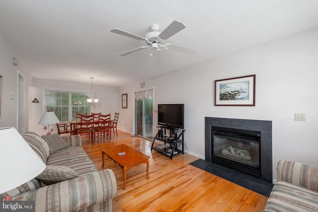 living room with light hardwood / wood-style flooring and ceiling fan with notable chandelier