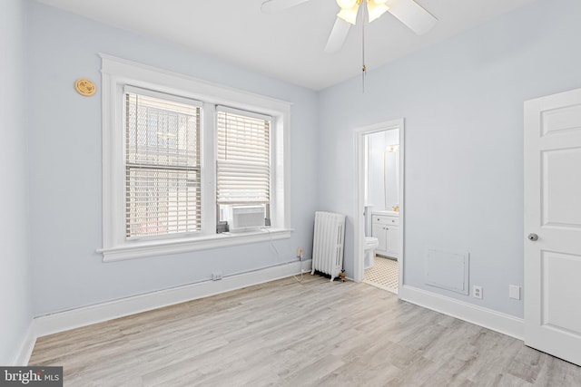 empty room with baseboards, light wood-style floors, a ceiling fan, and radiator