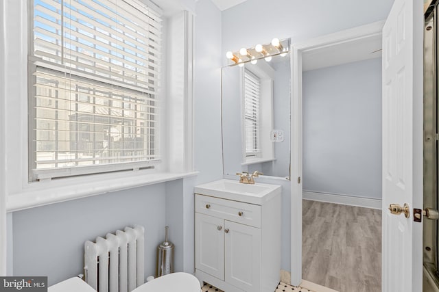 bathroom featuring radiator, plenty of natural light, vanity, and wood finished floors