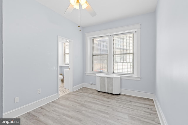 spare room with baseboards, a ceiling fan, and light wood-style floors