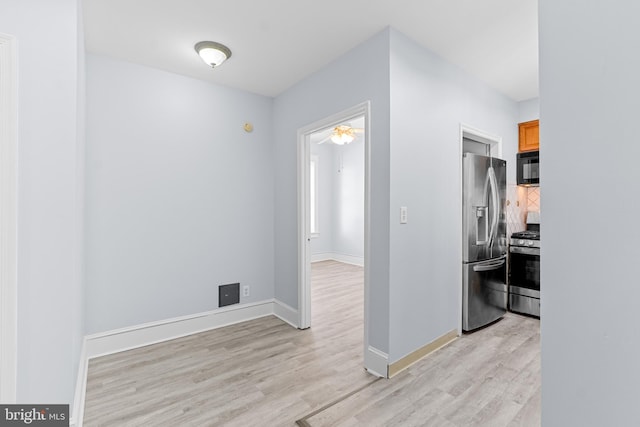 corridor featuring light wood-type flooring and baseboards