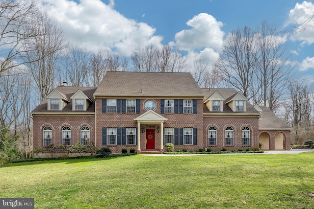 colonial inspired home featuring brick siding and a front lawn