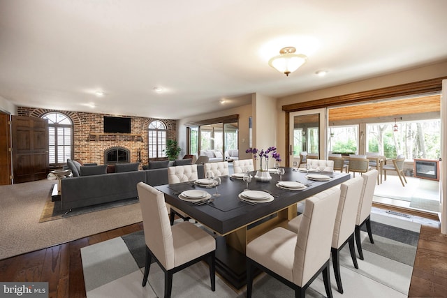 dining room featuring a brick fireplace, visible vents, plenty of natural light, and hardwood / wood-style floors