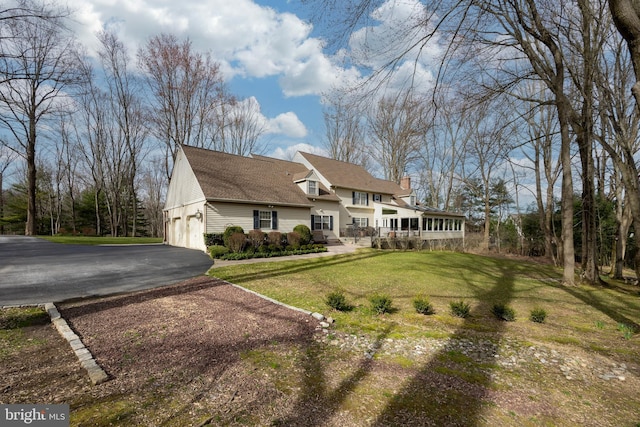 view of front of house with a garage, a chimney, and a front lawn