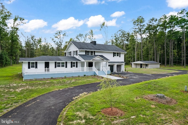 view of front of property featuring a porch, a garage, an outdoor structure, and a front yard