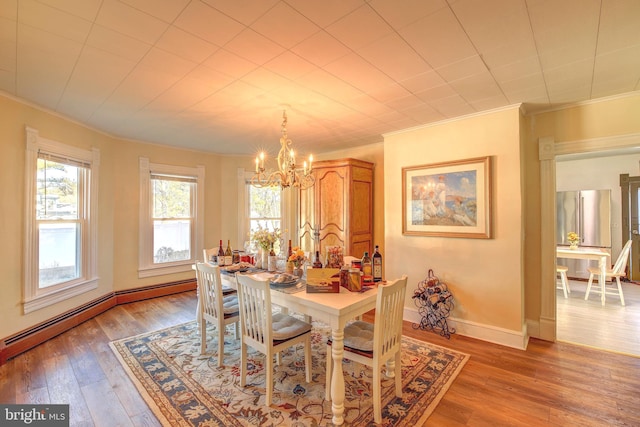 dining space with a baseboard radiator, an inviting chandelier, hardwood / wood-style flooring, and crown molding