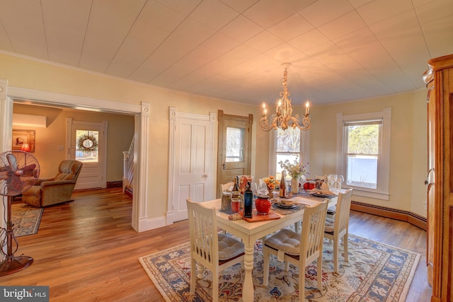 dining area with a baseboard radiator, crown molding, wood-type flooring, and a chandelier