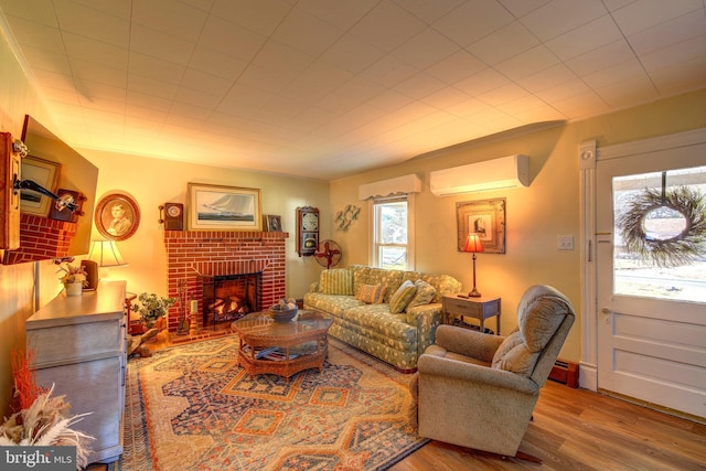 living room with a brick fireplace, an AC wall unit, hardwood / wood-style floors, and a wealth of natural light