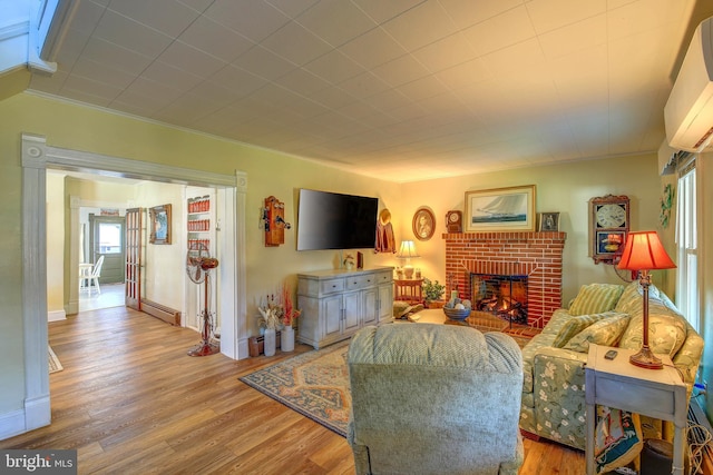 living room featuring a fireplace, plenty of natural light, a baseboard heating unit, and wood-type flooring