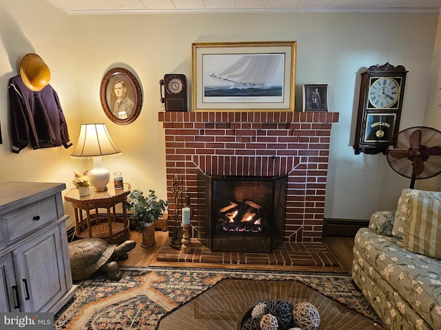 living room featuring wood-type flooring, a fireplace, and crown molding