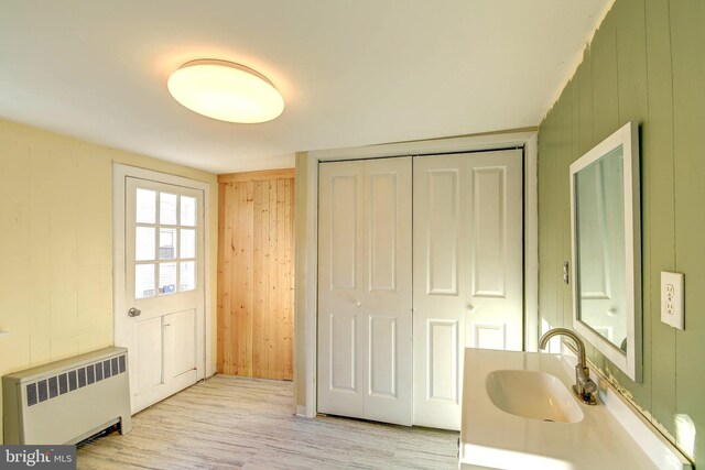 interior space with radiator, sink, and wooden walls