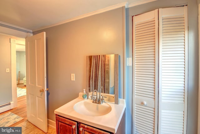 bathroom featuring a baseboard heating unit, ornamental molding, vanity, and wood-type flooring