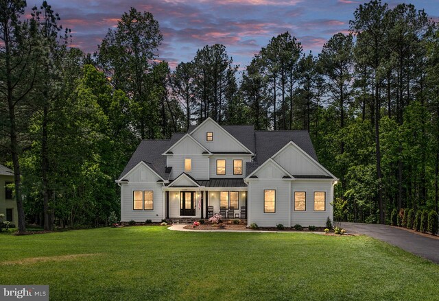 modern farmhouse featuring covered porch and a yard