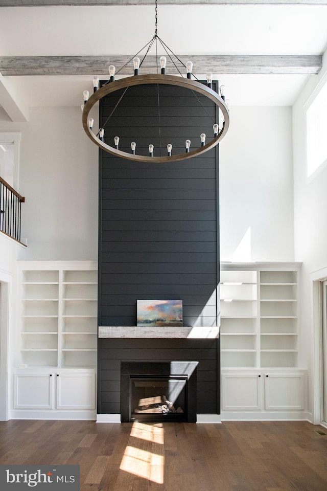 interior details featuring beam ceiling, wood-type flooring, and a large fireplace