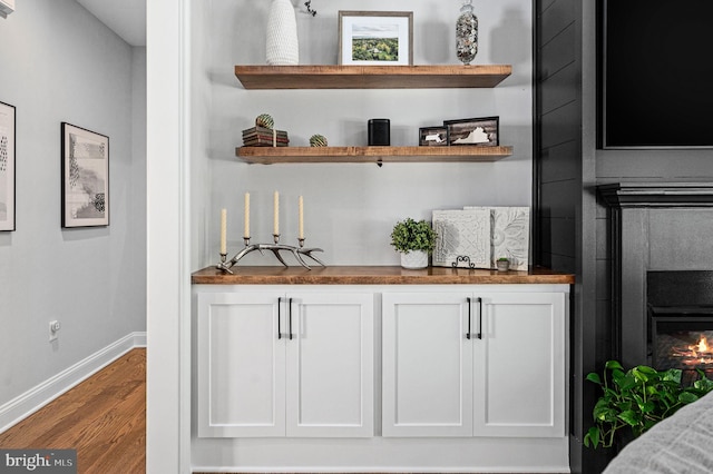 bar featuring hardwood / wood-style floors and white cabinets