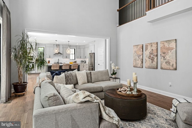 living room featuring sink, hardwood / wood-style flooring, and a high ceiling