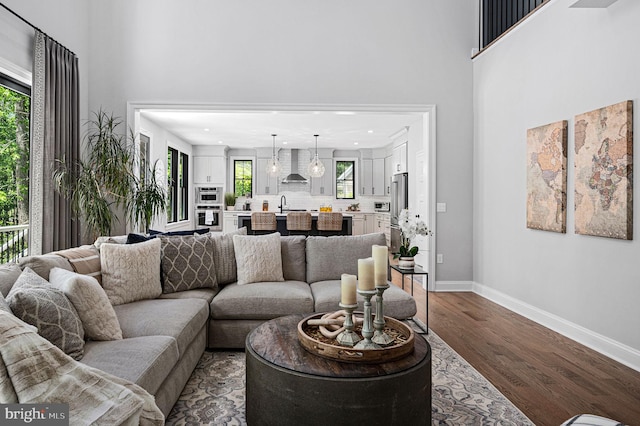 living room with dark wood-type flooring, sink, and a towering ceiling