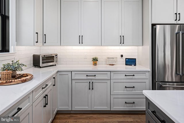 kitchen featuring dark hardwood / wood-style flooring, light stone countertops, backsplash, and high quality fridge