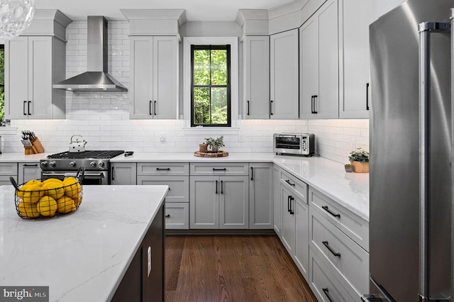 kitchen featuring dark hardwood / wood-style floors, backsplash, high end appliances, light stone counters, and wall chimney range hood