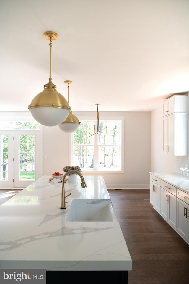 kitchen featuring sink, light stone counters, decorative light fixtures, dark hardwood / wood-style flooring, and white cabinets