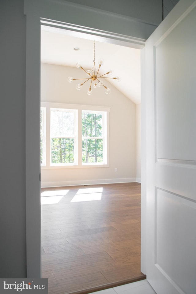 empty room with an inviting chandelier and wood-type flooring