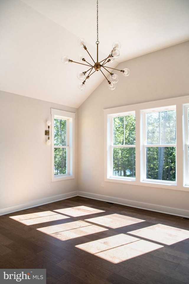 spare room featuring dark hardwood / wood-style flooring, lofted ceiling, a chandelier, and a healthy amount of sunlight