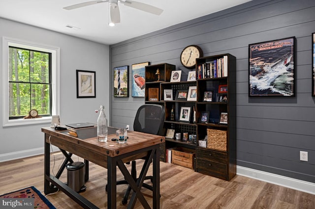 office space with light hardwood / wood-style flooring, ceiling fan, and wood walls