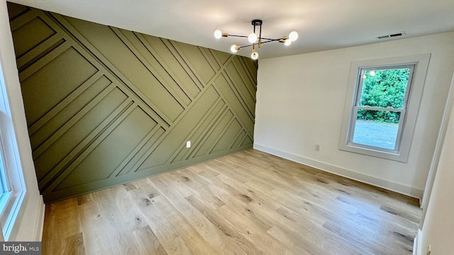 empty room with light wood-type flooring and a chandelier