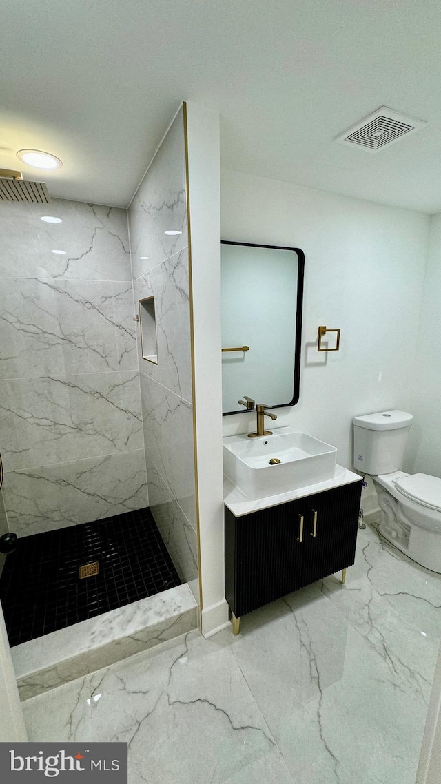 bathroom featuring tile patterned floors, a tile shower, vanity, and toilet