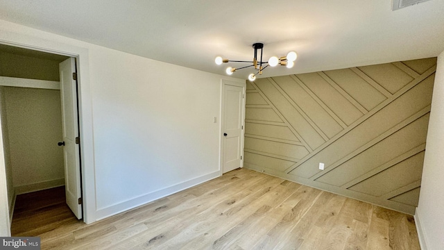 unfurnished room featuring a notable chandelier and light hardwood / wood-style floors