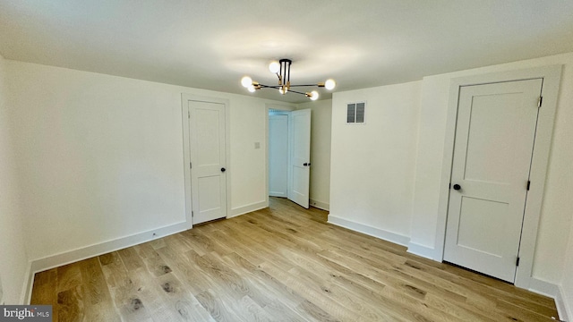 unfurnished bedroom featuring a notable chandelier and light hardwood / wood-style floors