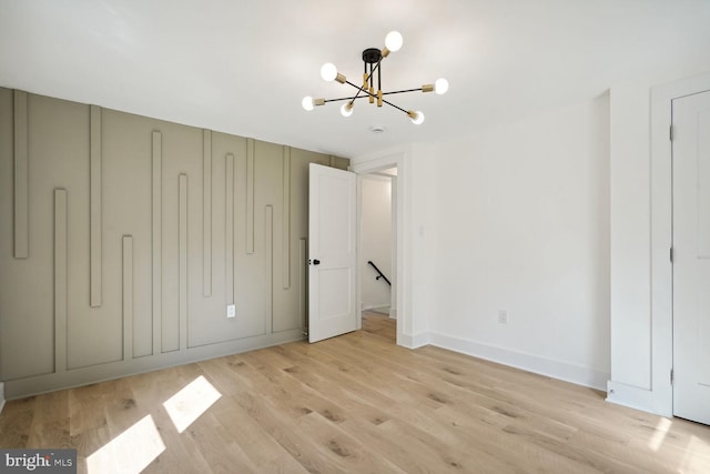 unfurnished bedroom with light wood-type flooring and an inviting chandelier