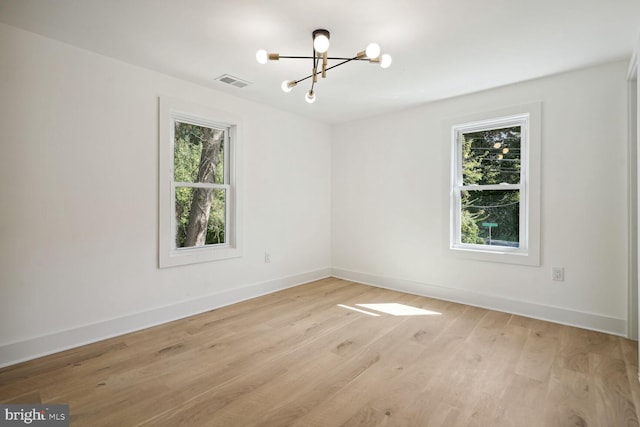 spare room featuring an inviting chandelier and light wood-type flooring