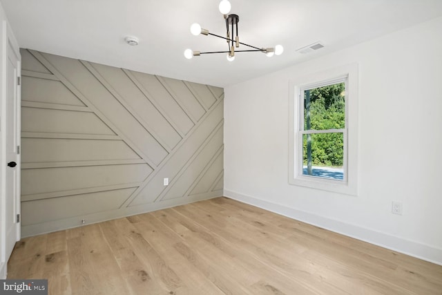 spare room featuring light hardwood / wood-style flooring and a chandelier