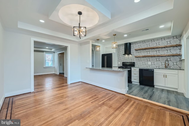 kitchen with wood-type flooring, white cabinetry, a raised ceiling, and black appliances