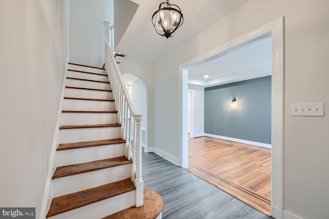 stairs with hardwood / wood-style floors and an inviting chandelier