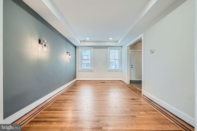 spare room with hardwood / wood-style flooring and a tray ceiling