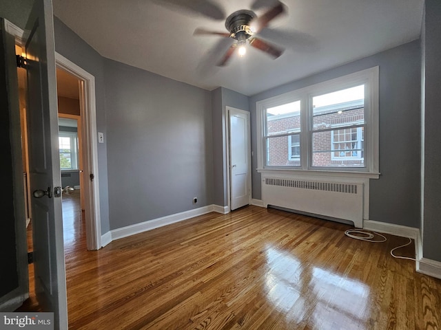 spare room featuring ceiling fan, radiator, and hardwood / wood-style flooring