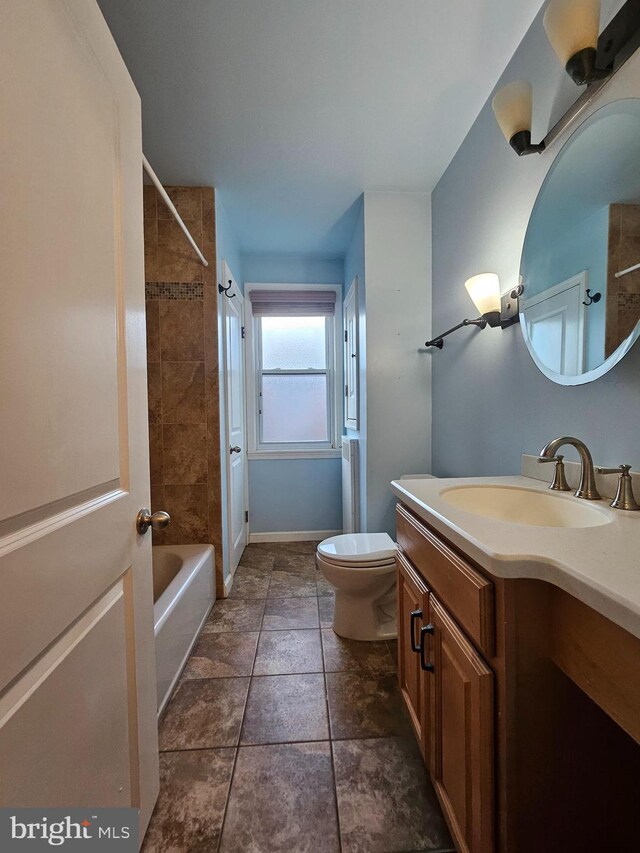 full bathroom with tile patterned floors, tiled shower / bath, vanity, and toilet