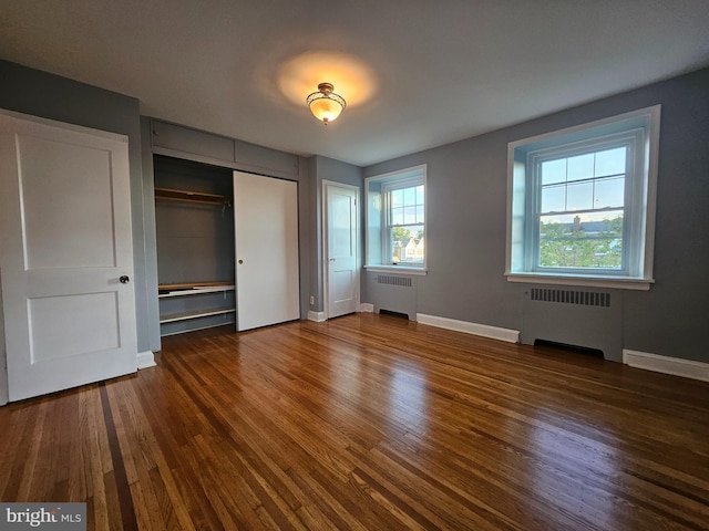 unfurnished bedroom with radiator and dark hardwood / wood-style floors