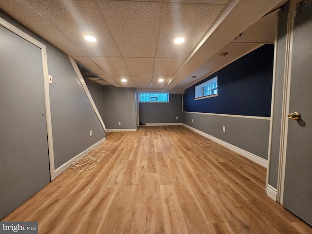 basement with a drop ceiling and light hardwood / wood-style flooring