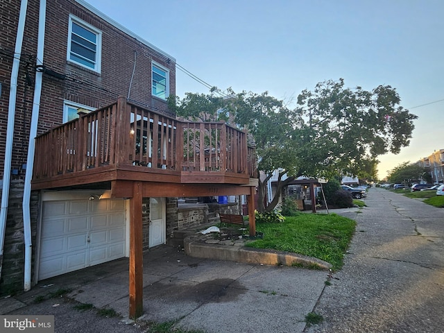 property exterior at dusk featuring a deck and a garage